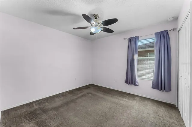 an empty room with a window and ceiling fan