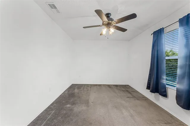 an empty room with a window and a fan