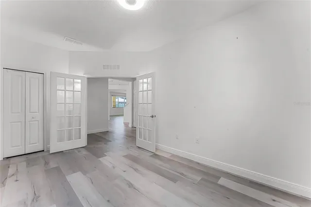 a view of an empty room with wooden floor and closet area