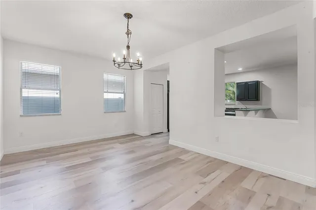 a view of a hallway with wooden floor and a kitchen