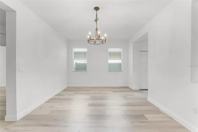 a view of an empty room with wooden floor and windows