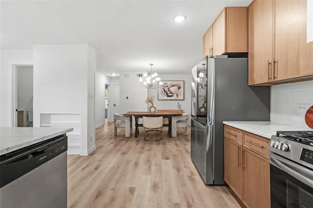 a kitchen with stainless steel appliances granite countertop a refrigerator a stove and a wooden floors