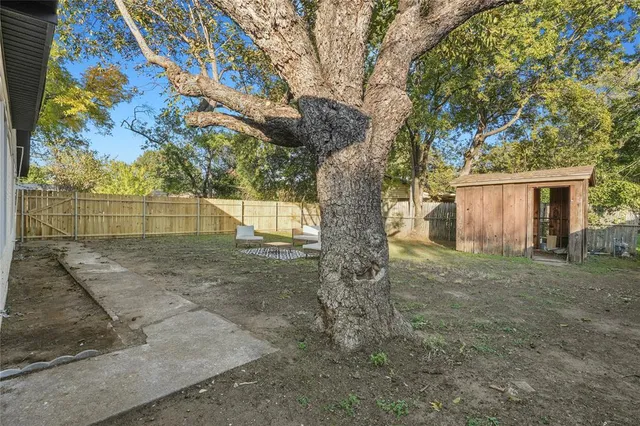 a view of backyard with wooden fence and large trees