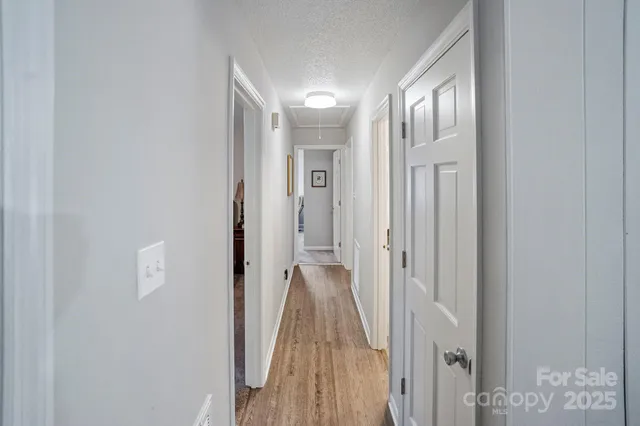 a view of a hallway with wooden floor and a bathroom