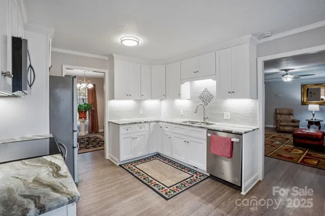 a kitchen with granite countertop a sink cabinets and wooden floor