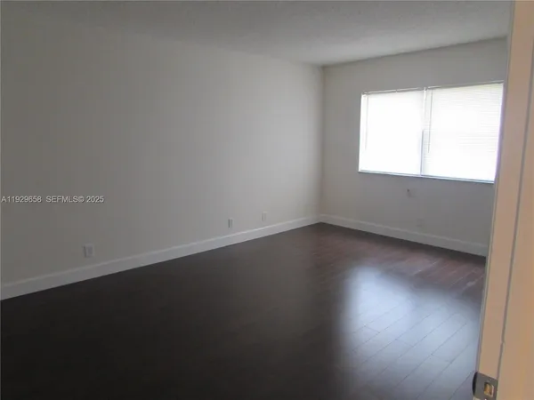 a view of an empty room with wooden floor and closet