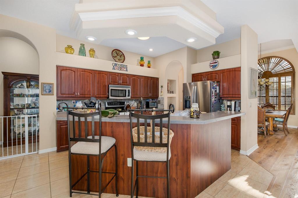 427 Archway Drive Spring Hill, FL 34608 - Photo 24 of 68 a kitchen with stainless steel appliances kitchen island granite countertop a refrigerator a stove a sink a dining table and chairs with wooden floor