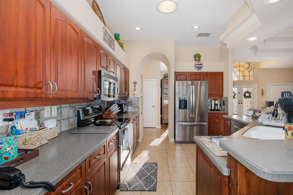 427 Archway Drive Spring Hill, FL 34608 - Photo 25 of 68 a kitchen with stainless steel appliances granite countertop a sink refrigerator and cabinets