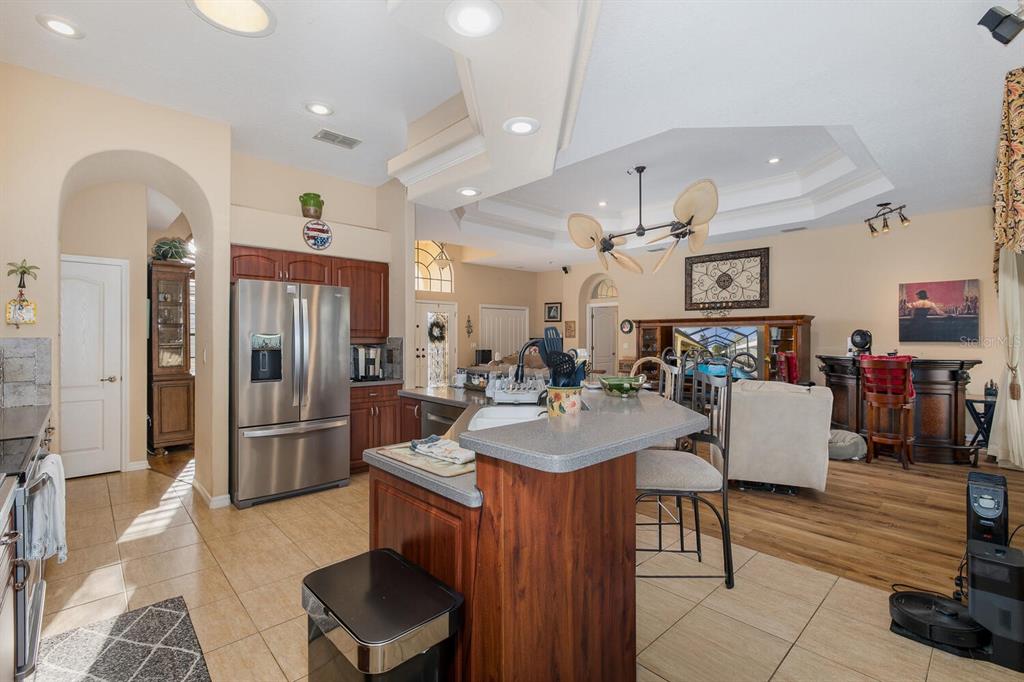 427 Archway Drive Spring Hill, FL 34608 - Photo 26 of 68 a kitchen with stainless steel appliances kitchen island granite countertop a refrigerator a stove and a dining table with wooden floor