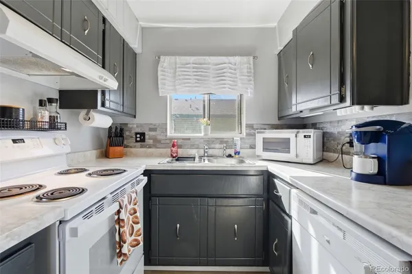 a kitchen with granite countertop a sink stove and cabinets