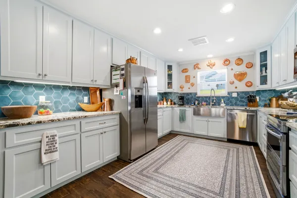 a kitchen with white cabinets a sink dishwasher and a stove with wooden floor