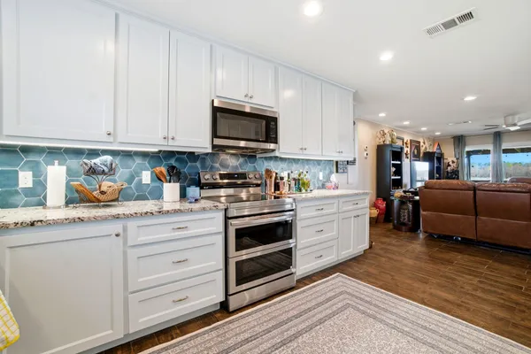a kitchen with granite countertop white cabinets and white appliances