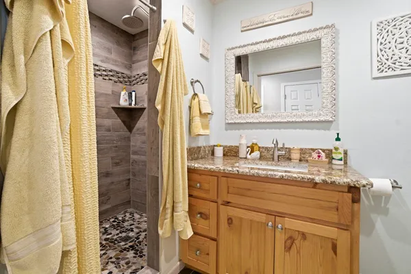 a bathroom with a granite countertop sink a mirror a vanity and a shower