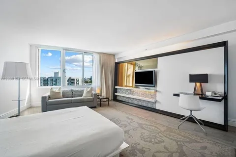 a spacious bedroom with a bed and a flat screen tv