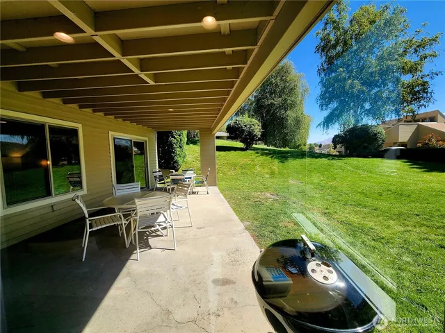 a view of a backyard with table and chairs potted plants and large tree
