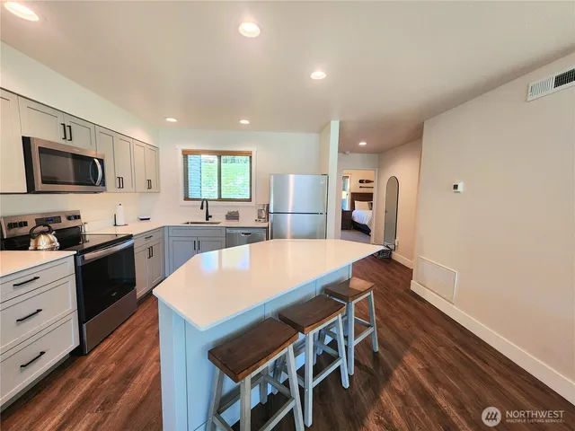 a large kitchen with cabinets wooden floor and stainless steel appliances
