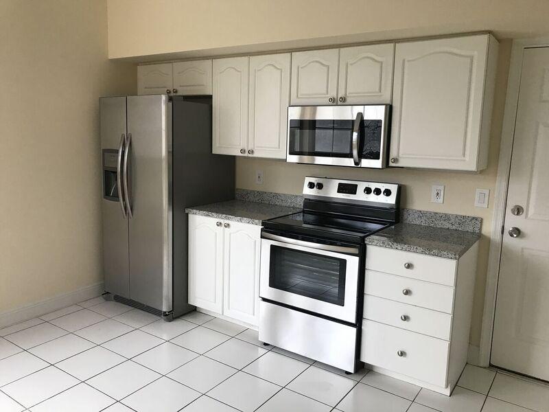 5212 Edenwood Road Riviera Beach, FL 33418 - Photo 2 of 7 a kitchen with white cabinets and stainless steel appliances