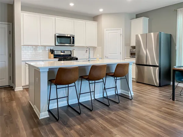 a kitchen with a sink a microwave a refrigerator and wooden floor