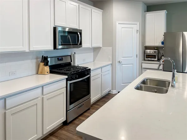 a kitchen with granite countertop white cabinets and stainless steel appliances