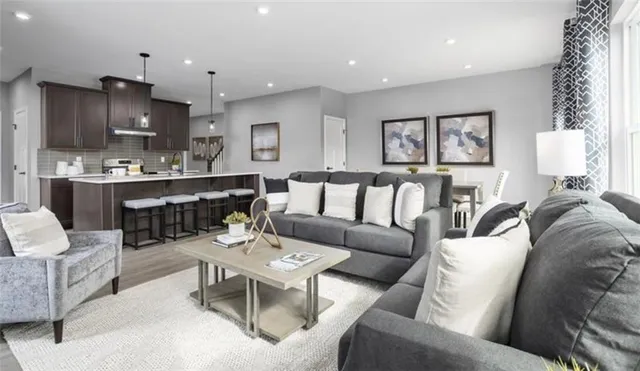 a living room with furniture kitchen view and a wooden floor