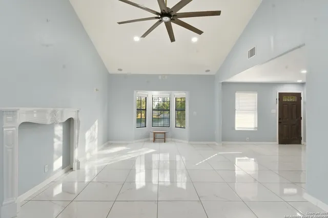 a view of an empty room with window and chandelier fan