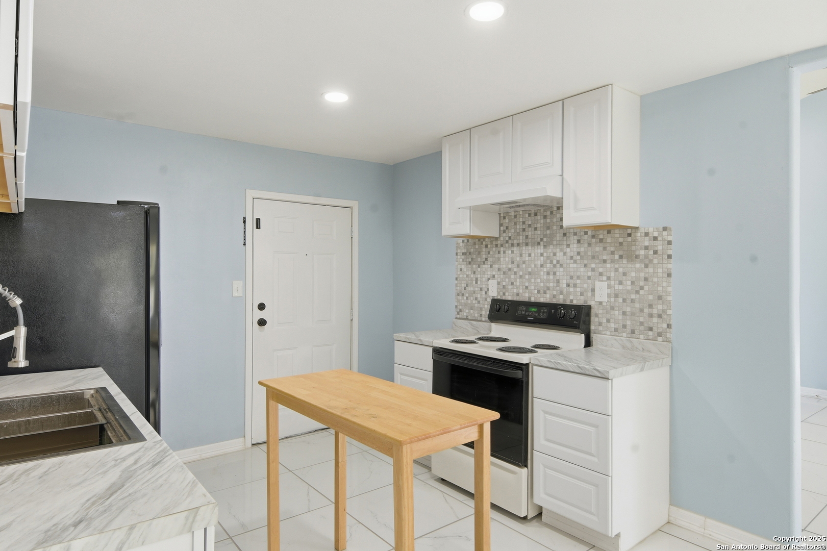521 Old Carrizo Road Uvalde, TX 78801 - Photo 8 of 31 a kitchen that has a microwave a stove white cabinetry and a refrigerator