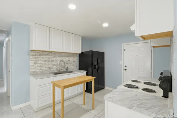 a kitchen with a sink a refrigerator and cabinets