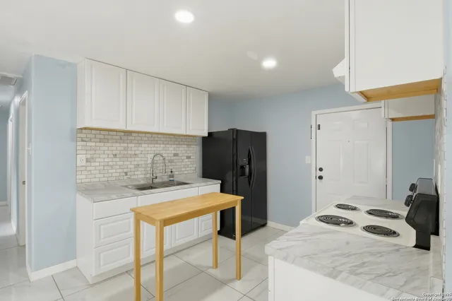 a kitchen with a sink a refrigerator and cabinets