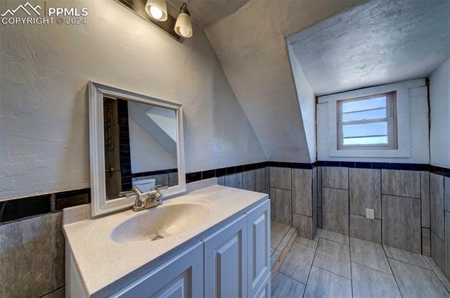 19350 Lemesany Road Calhan, CO 80808 - Photo 37 of 46 Bathroom featuring vanity, tile, tile shower, and lofted ceiling