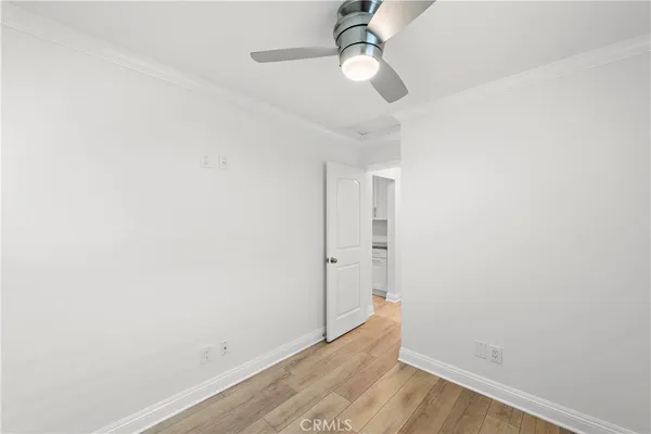 an empty room with wooden floor fan and window