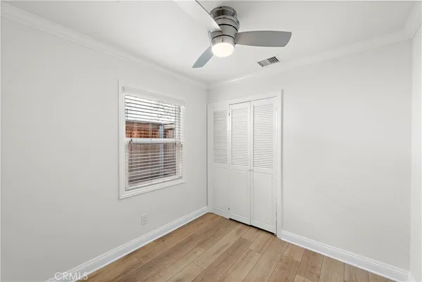 an empty room with wooden floor chandelier fan and windows