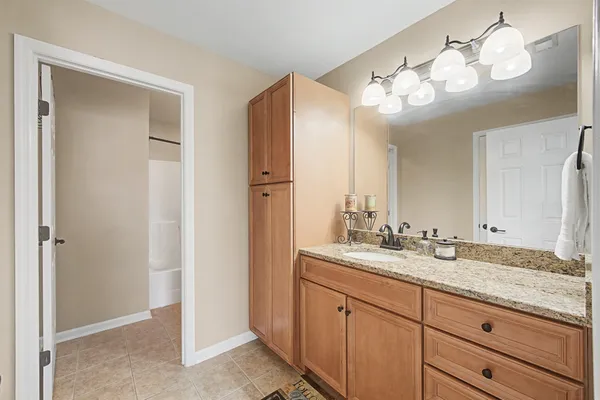 a bathroom with a granite countertop sink a light fixture and a mirror