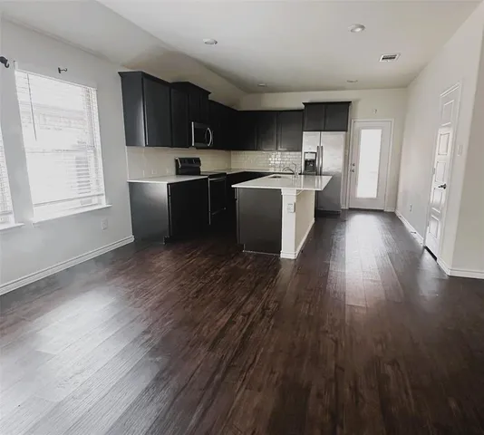 a kitchen with wooden floors and wooden cabinets