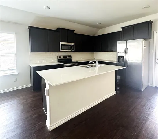 a kitchen with stainless steel appliances a refrigerator and a stove top oven