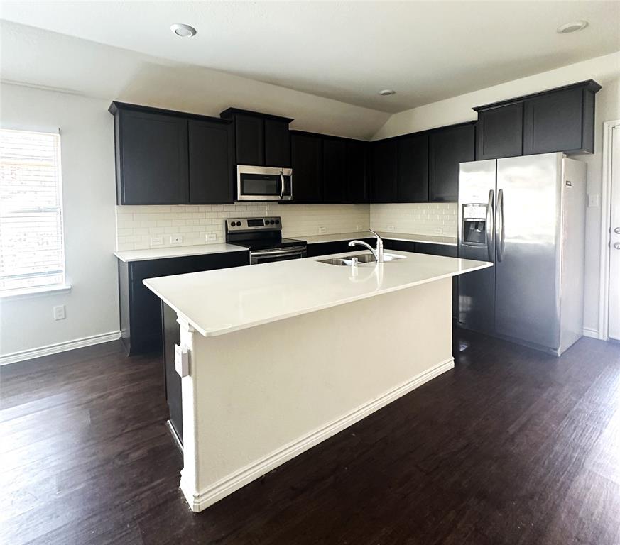 223 Garden Grove Drive Waxahachie, TX 75165 - Photo 4 of 24 a kitchen with stainless steel appliances a refrigerator and a stove top oven