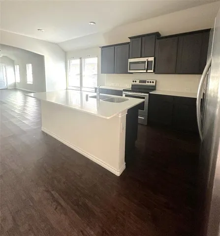 a kitchen with stainless steel appliances a sink a stove a refrigerator and cabinets