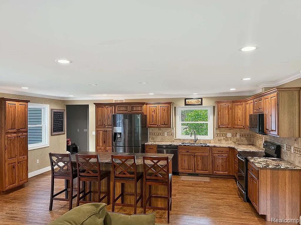 1555 Thompson Road Bad Axe, MI 48413 - Photo 5 of 14 Kitchen featuring extensive wood-finish cabinetry, granite countertops, stainless steel appliances, and a tile backsplash