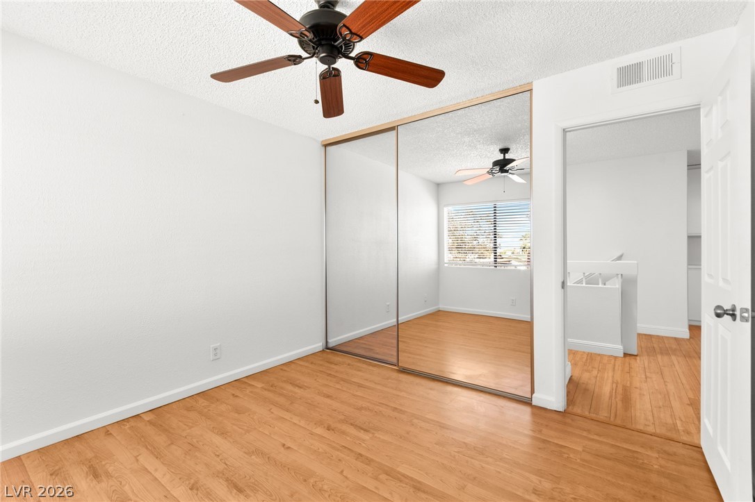 4430 Cranbrook Way Las Vegas, NV 89103 - Photo 45 of 50 Mirrored closet doors reflect a bright window and rich wood flooring in this comfortable bedroom.
