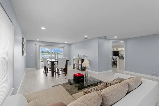 a living room with furniture and a dining table with wooden floor