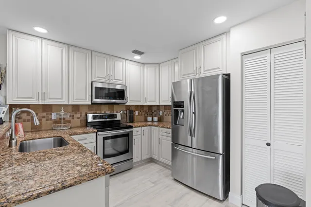 a kitchen with stainless steel appliances granite countertop a refrigerator sink and stove