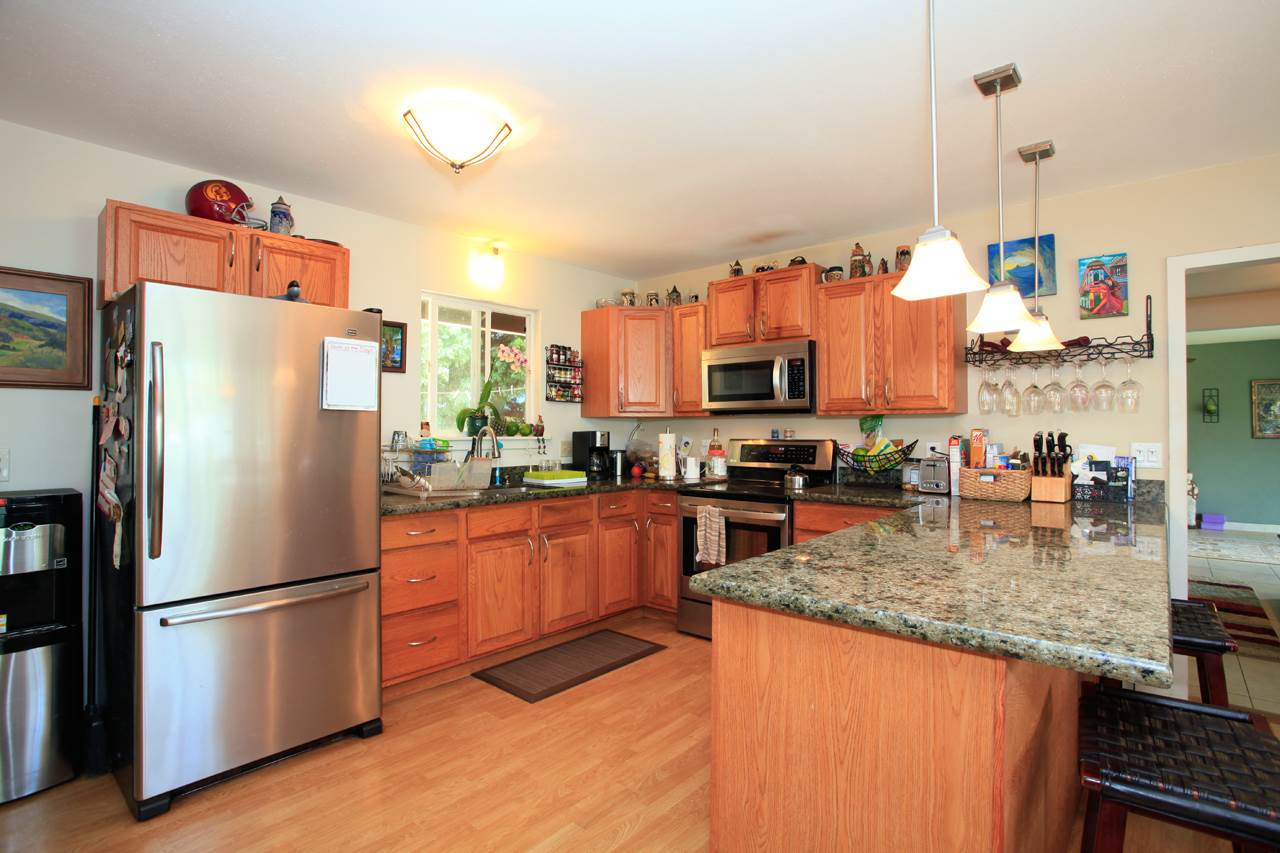 2811 Kokomo Road Haiku, HI 96708 - Photo 23 of 30 a kitchen with stainless steel appliances granite countertop a refrigerator a stove and a sink