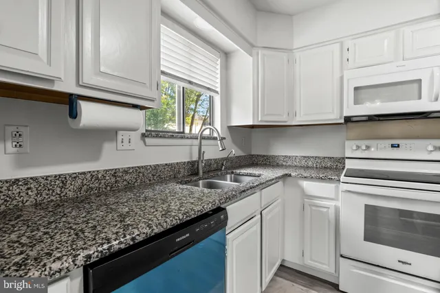 a kitchen with granite countertop white cabinets and a stove