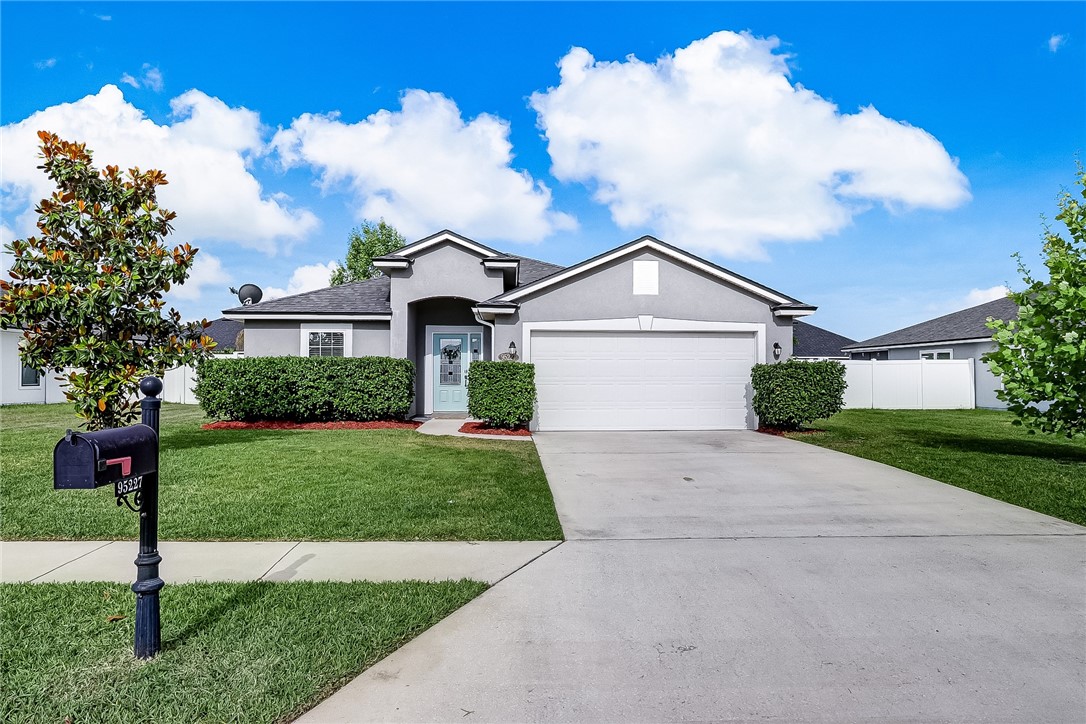 a view of a white house next to a yard with big trees