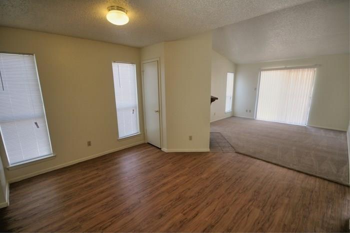 1906 West Loop, Unit D Austin, TX 78758 - Photo 2 of 5 Open-concept interior featuring wood-finish flooring, textured ceilings, multiple windows with blinds, and a sliding glass door