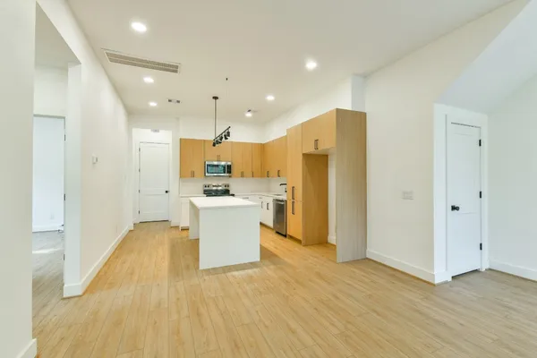 a view of kitchen with stainless steel appliances refrigerator oven and white cabinets with wooden floor