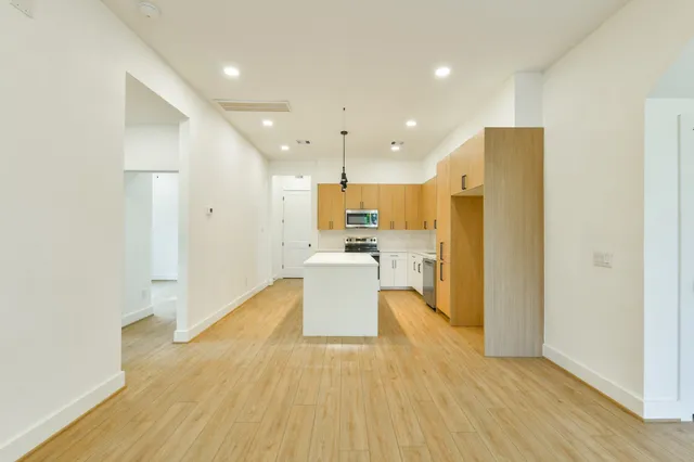 a view of a kitchen with kitchen island wooden floor center island and stainless steel appliances