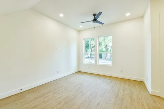 an empty room with wooden floor fan and windows