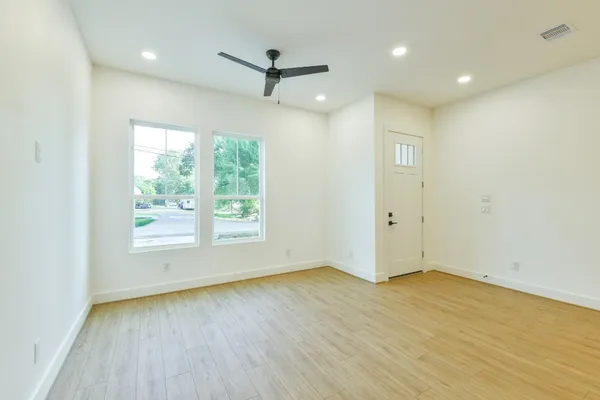 a view of a room with wooden floor a ceiling fan and windows