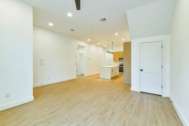 a view of an empty room with wooden floor and a window