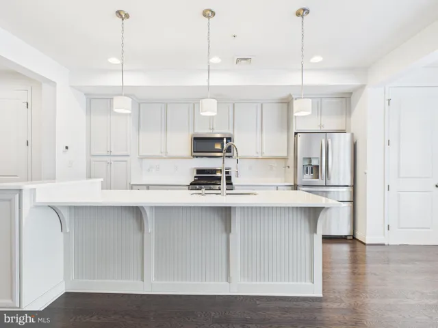 a kitchen with stainless steel appliances granite countertop a sink a stove a refrigerator and white cabinets